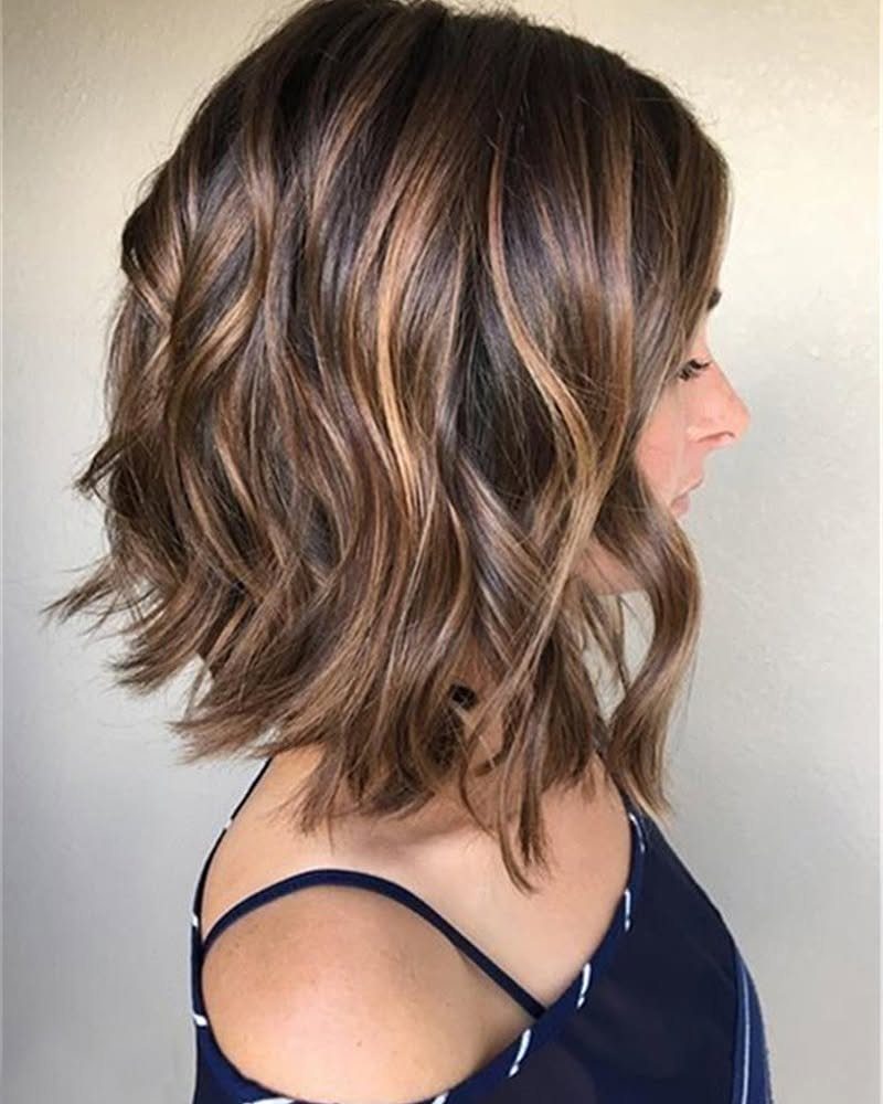 Shoulder-length highlighted hair with loose waves and feathered, tapered ends