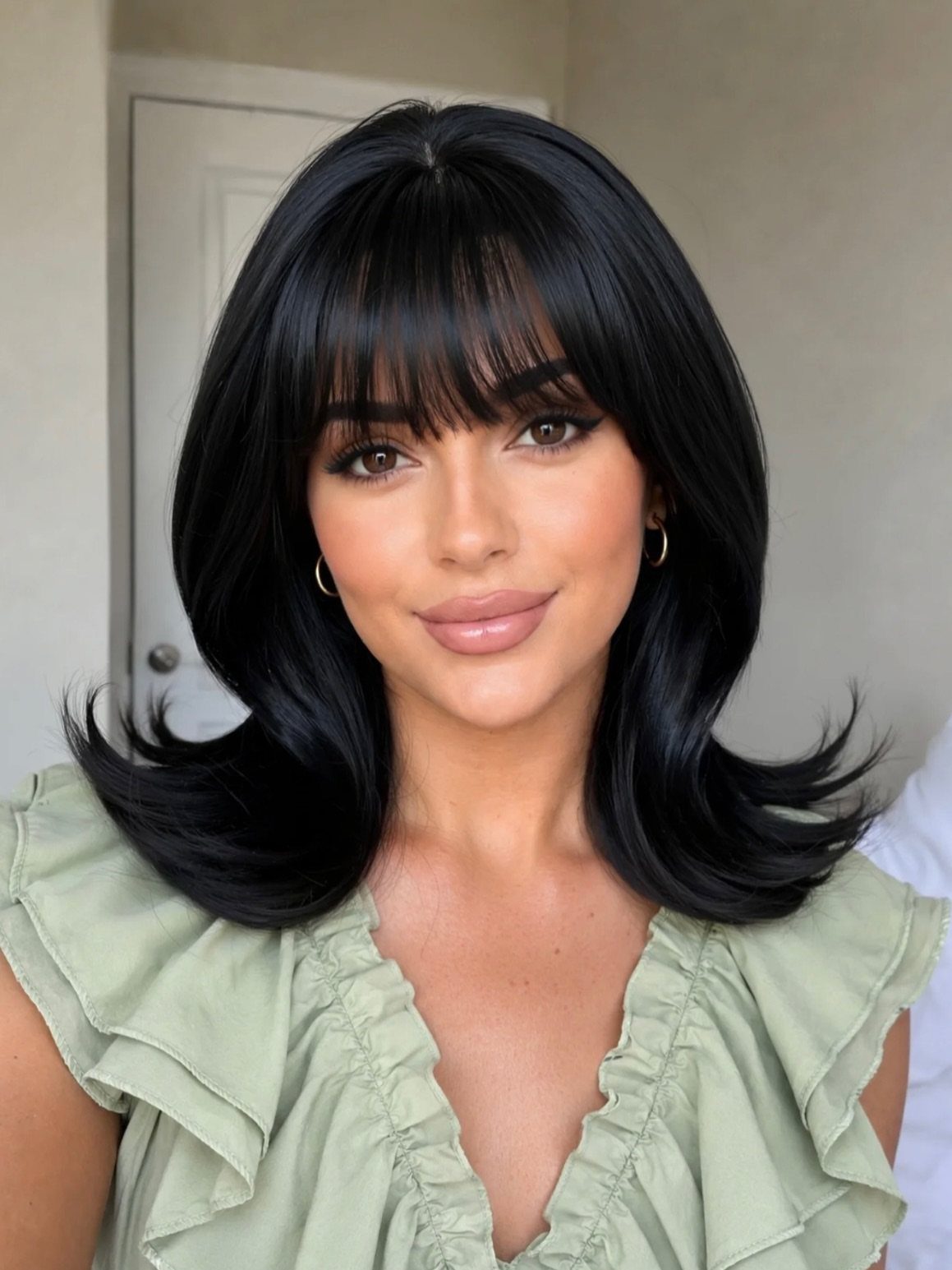 Woman with black shoulder-length hair and outward-flipped layered ends