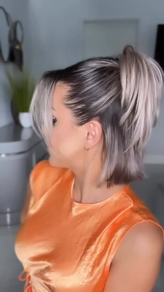 Woman wearing shoulder-length blonde hair with the upper section tied into a high ponytail