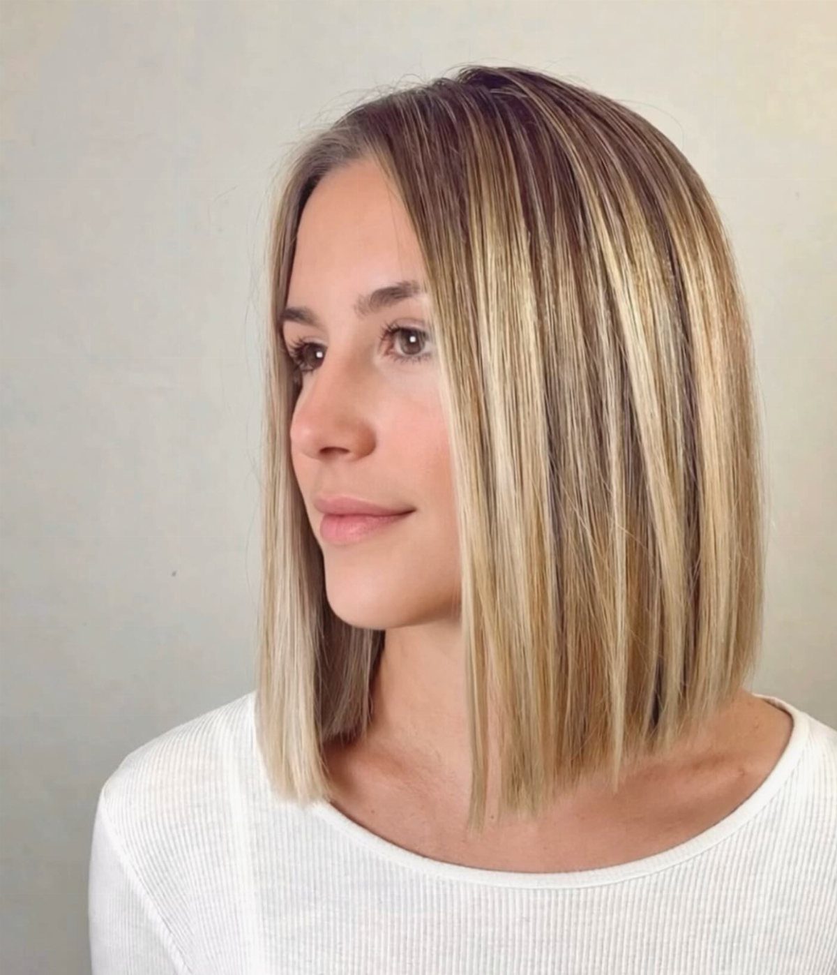 Woman showing a straight, collarbone-length blonde bob with dark roots