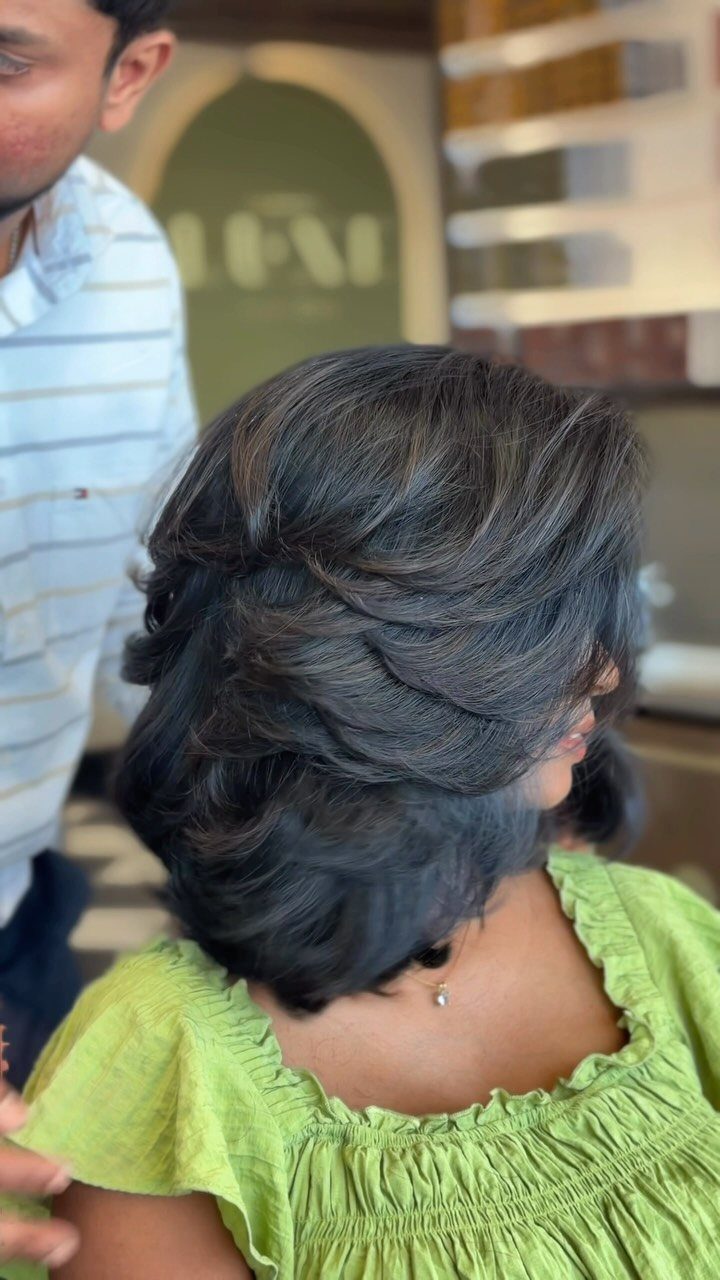 Woman showing a short, feathered dark layered haircut in a salon chair