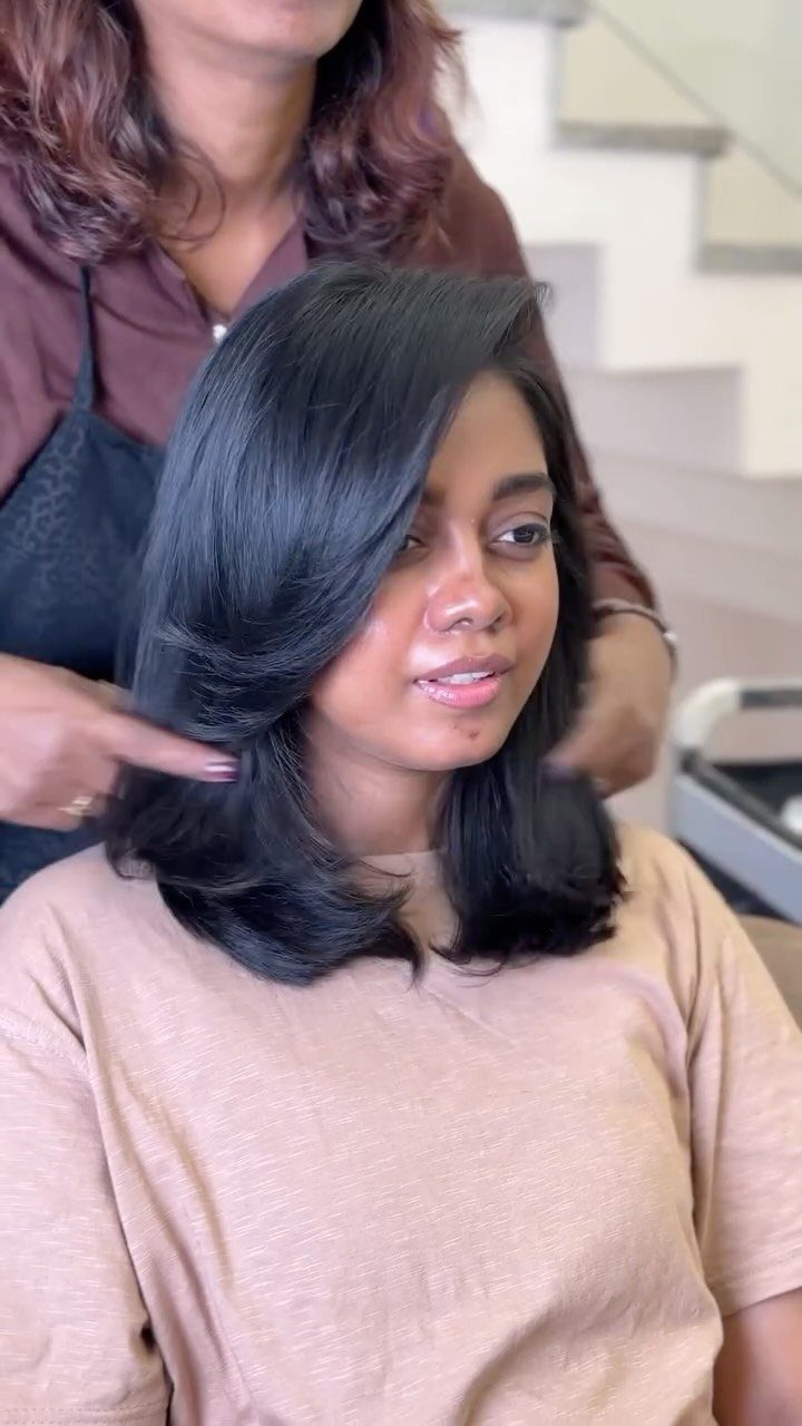 Woman displaying shoulder-length black hair with rounded layers and a deep side part