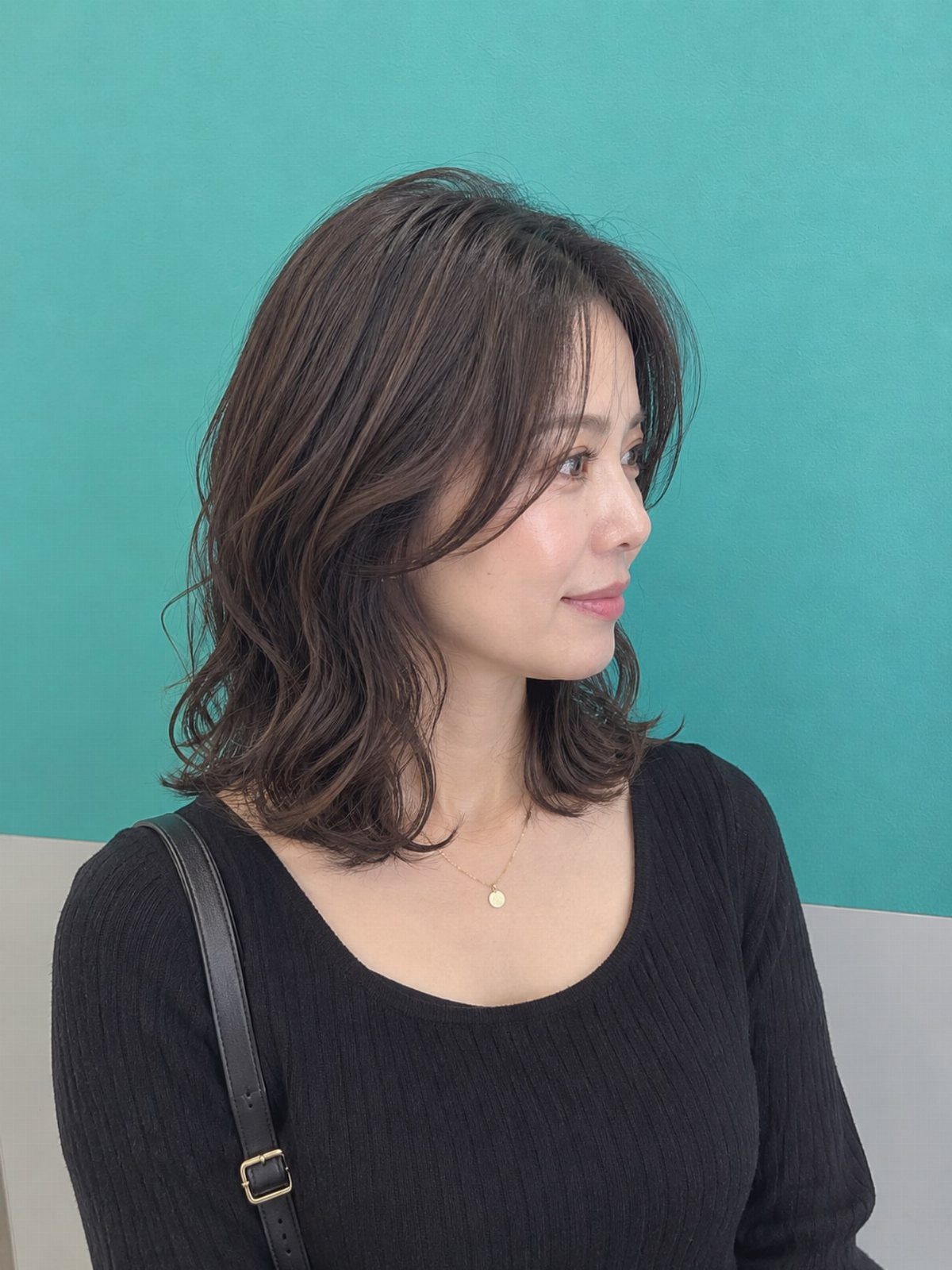 Woman with shoulder-length dark hair styled in loose, tousled waves