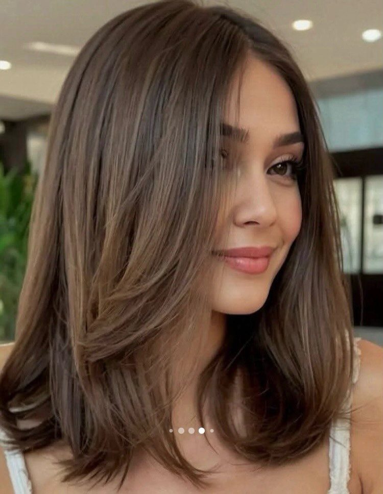 Woman showing a smooth, rounded shoulder-length brown blowout bob with soft layers