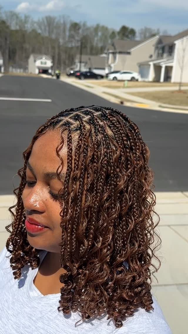 Woman wearing shoulder-length brown braids with curly ends outdoors