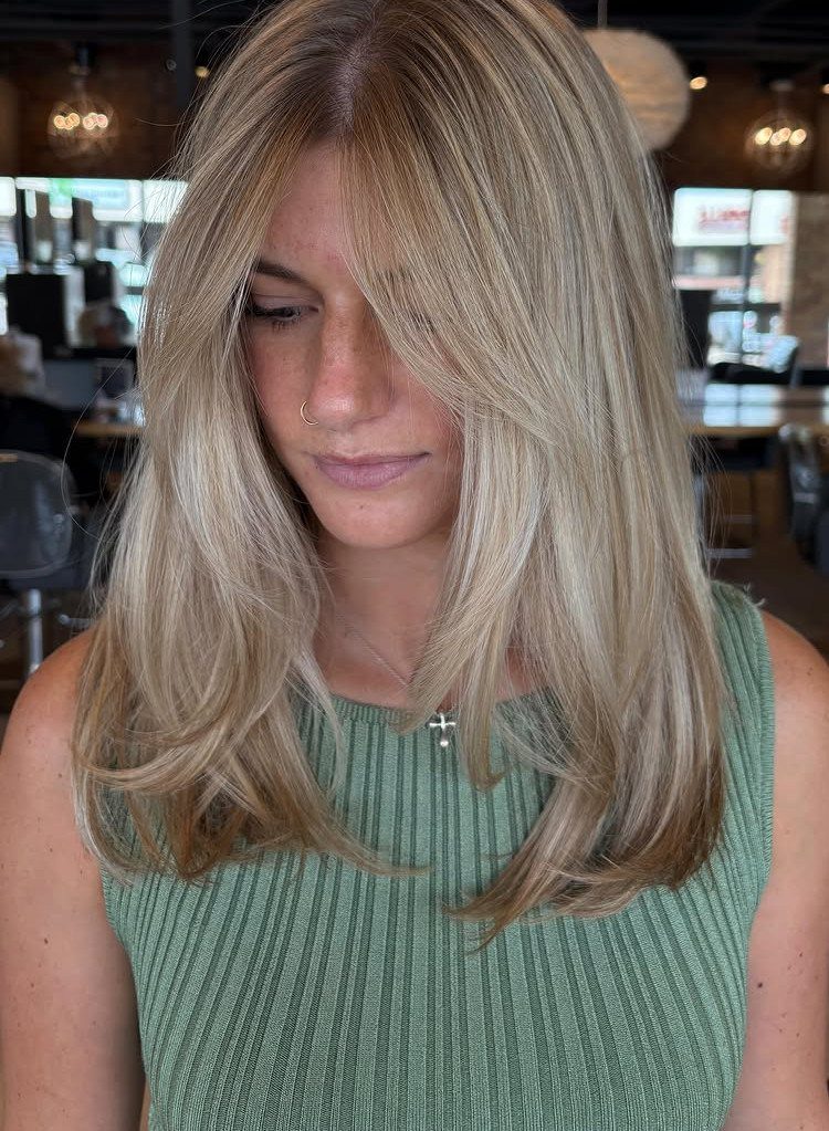 Woman displaying blonde face-framing layers with smooth, curled-under ends