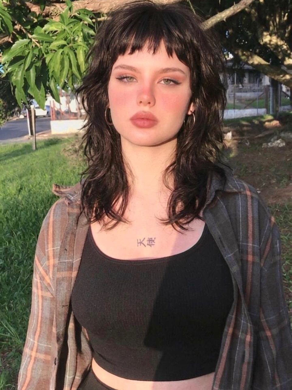 Woman with a dark layered shoulder-length haircut and short choppy bangs