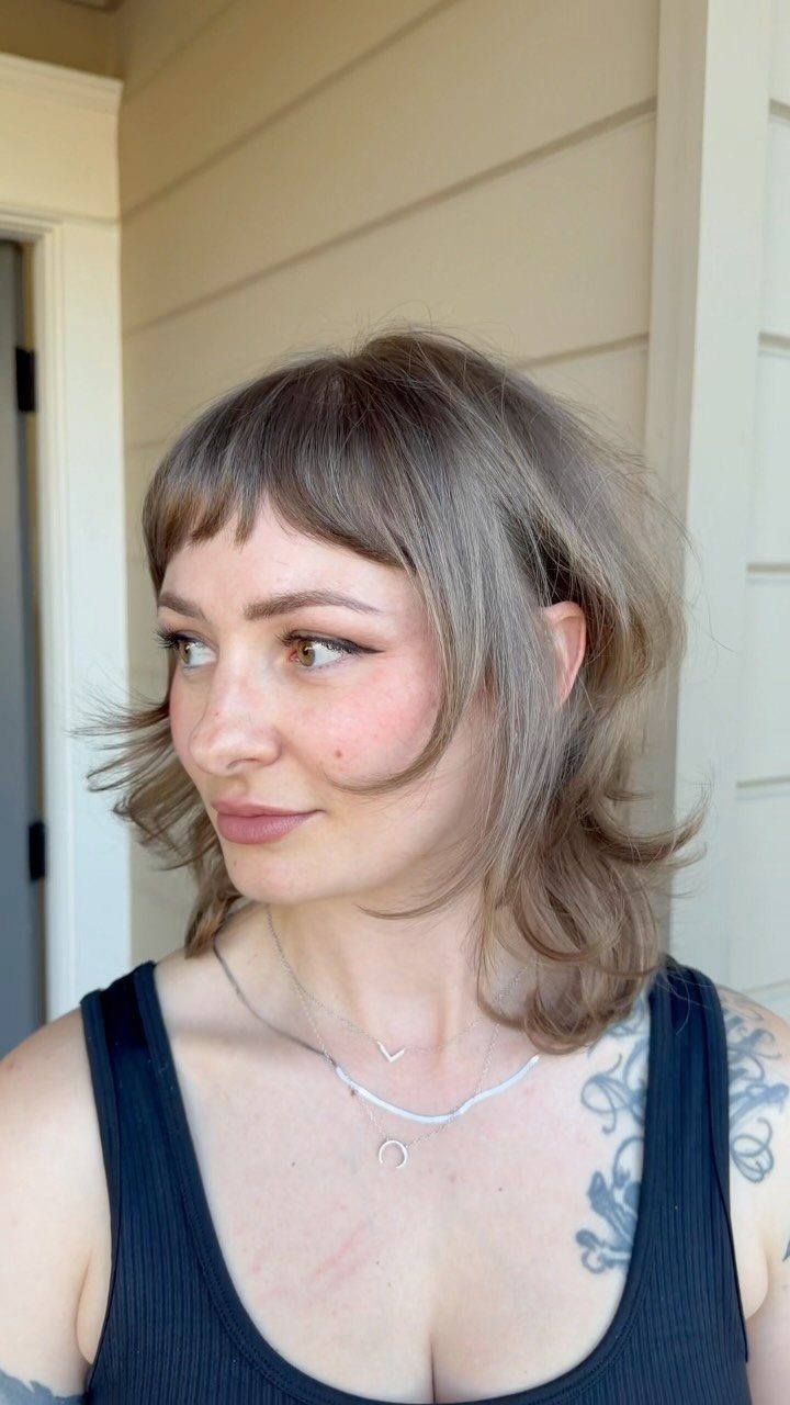 Woman showing a tousled shoulder-length shag with choppy bangs and layered ends