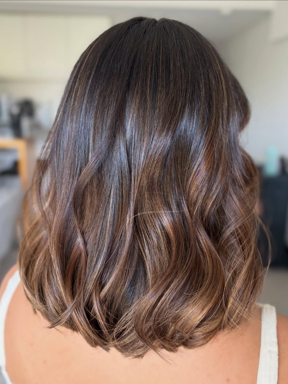 Shoulder-length wavy brown hair with subtle highlights and layered ends