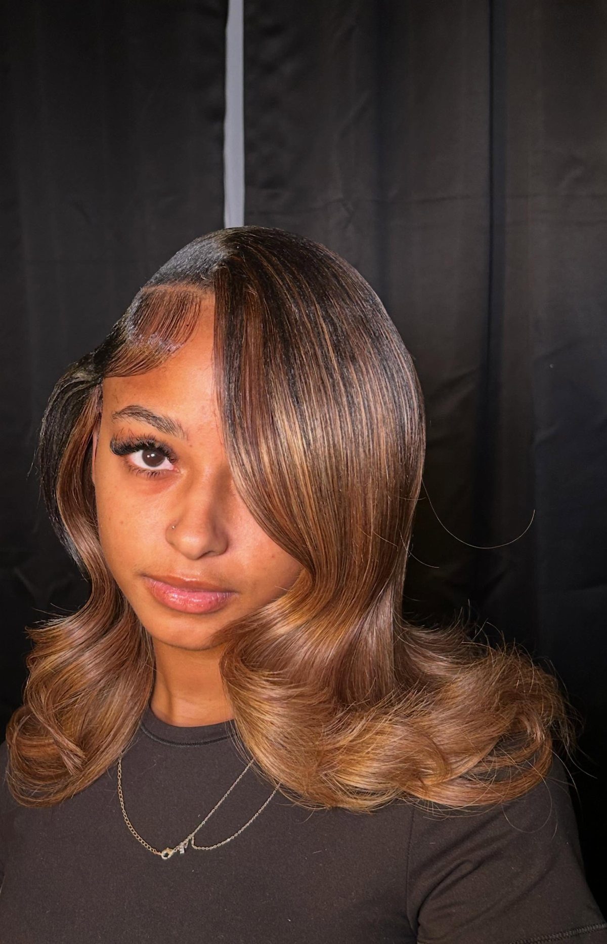 Woman with a side-parted shoulder-length brown haircut and curled ends