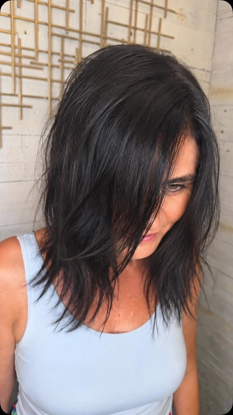 Woman showing dark shoulder-length hair with loose, soft long layers