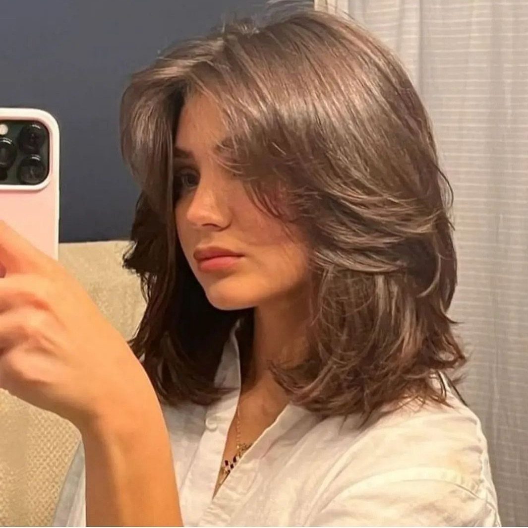 Layered brown shoulder-length haircut with swoopy face-framing sections