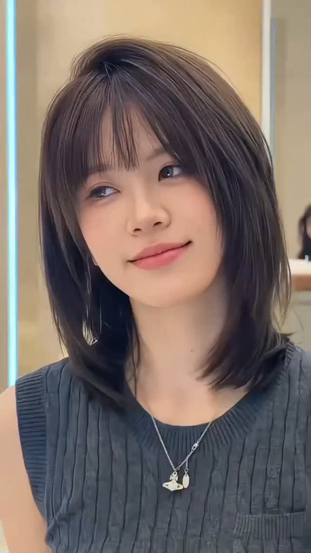Woman showing a dark shoulder-length bob haircut with wispy bangs