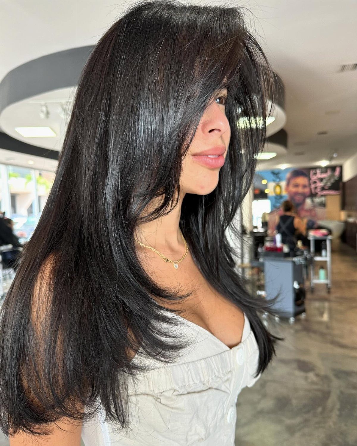 Woman with long dark layers and a thick side-swept fringe in a salon