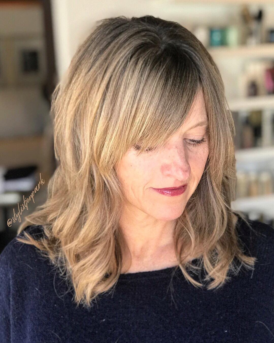 Woman with a layered blonde lob and long side-swept bangs