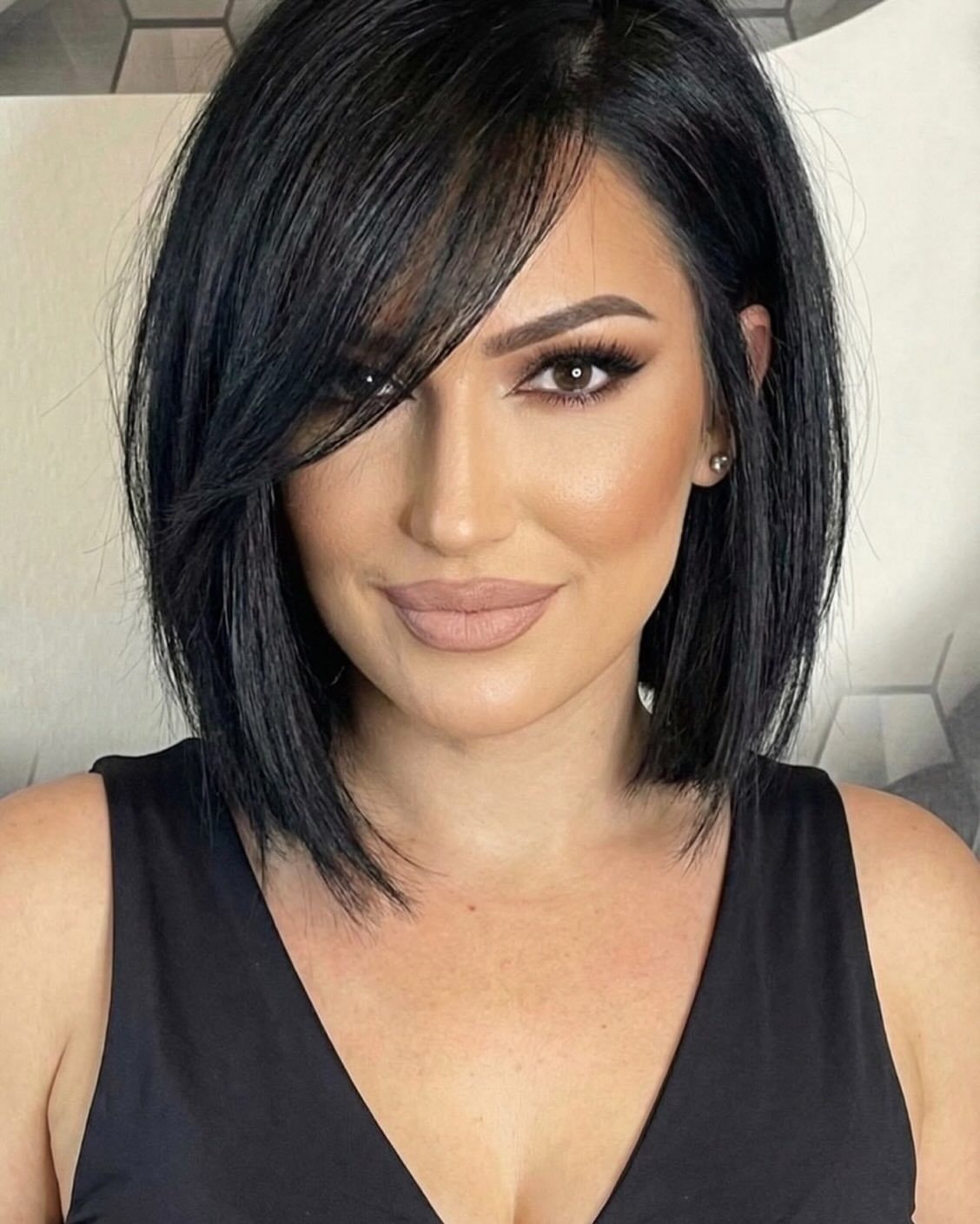 Woman with a sleek black A-line bob and long side-swept bangs