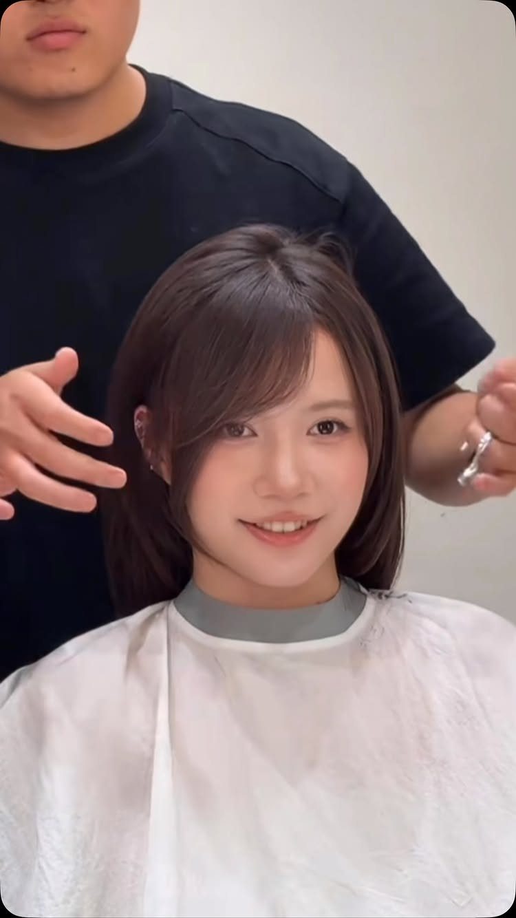 Woman in a salon with medium-length dark hair and side-swept bangs