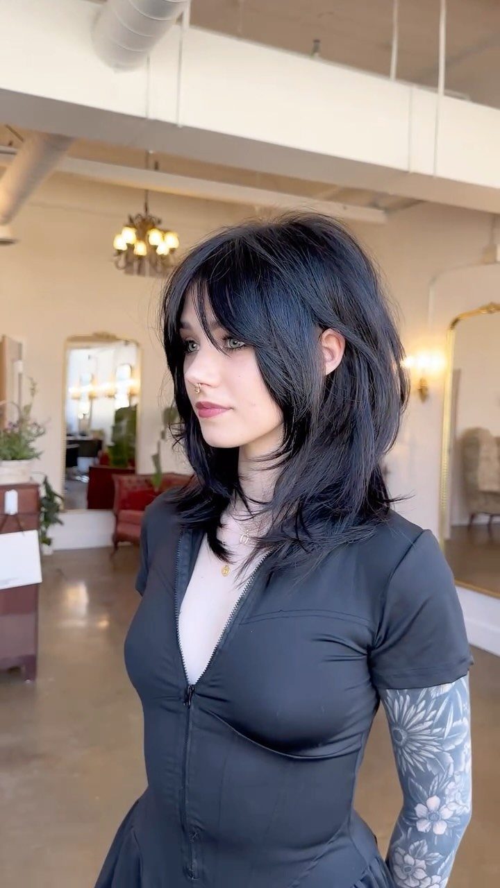 Woman with black layered hair and off-center, flipped face-framing bangs