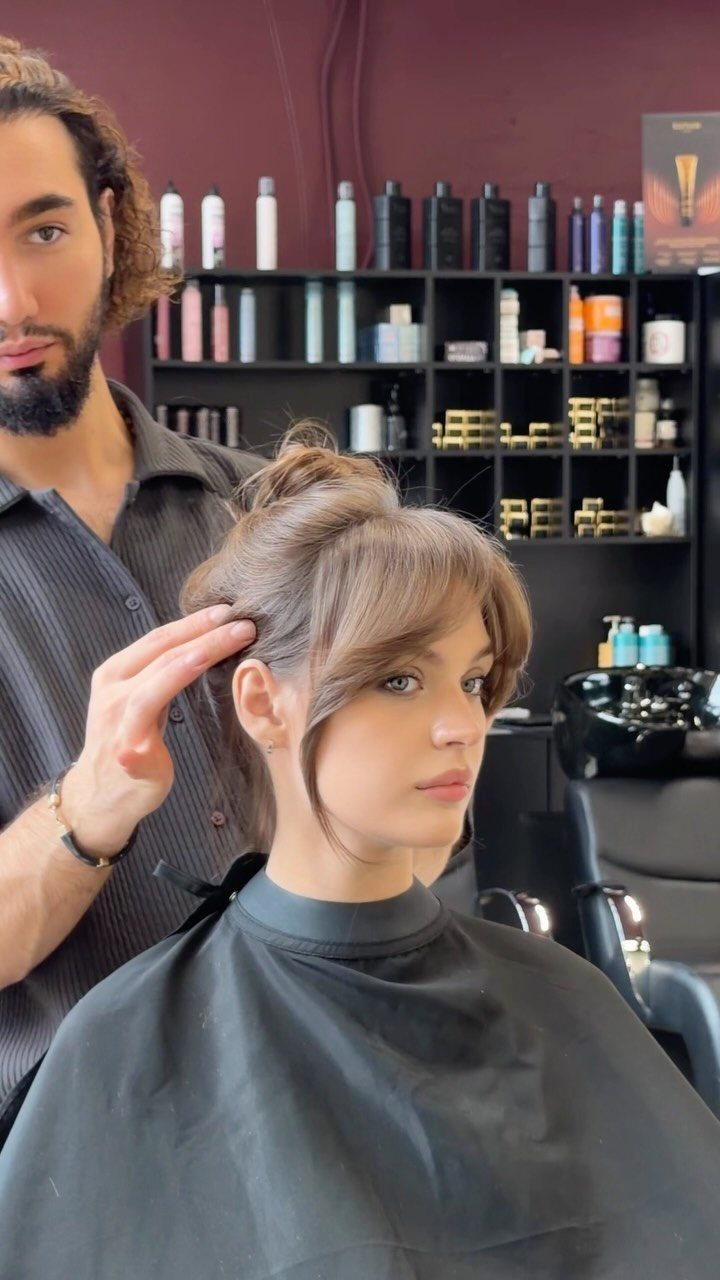 Woman with shoulder-length wavy hair and soft rounded side bangs in a salon
