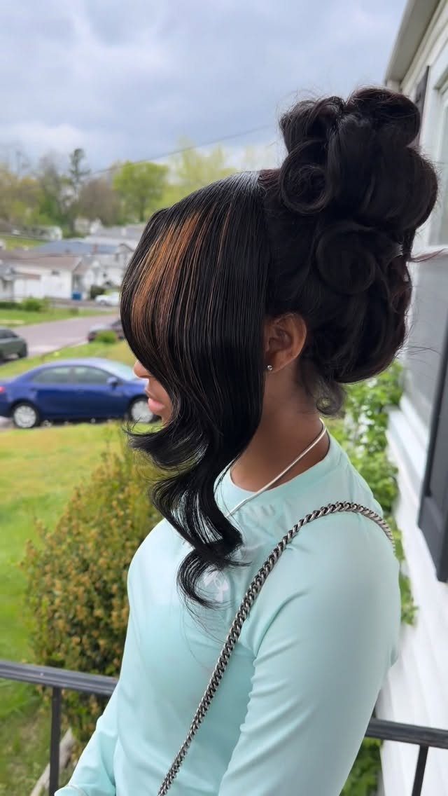 Side-swept dark bangs frame a curled updo as a person stands on a balcony