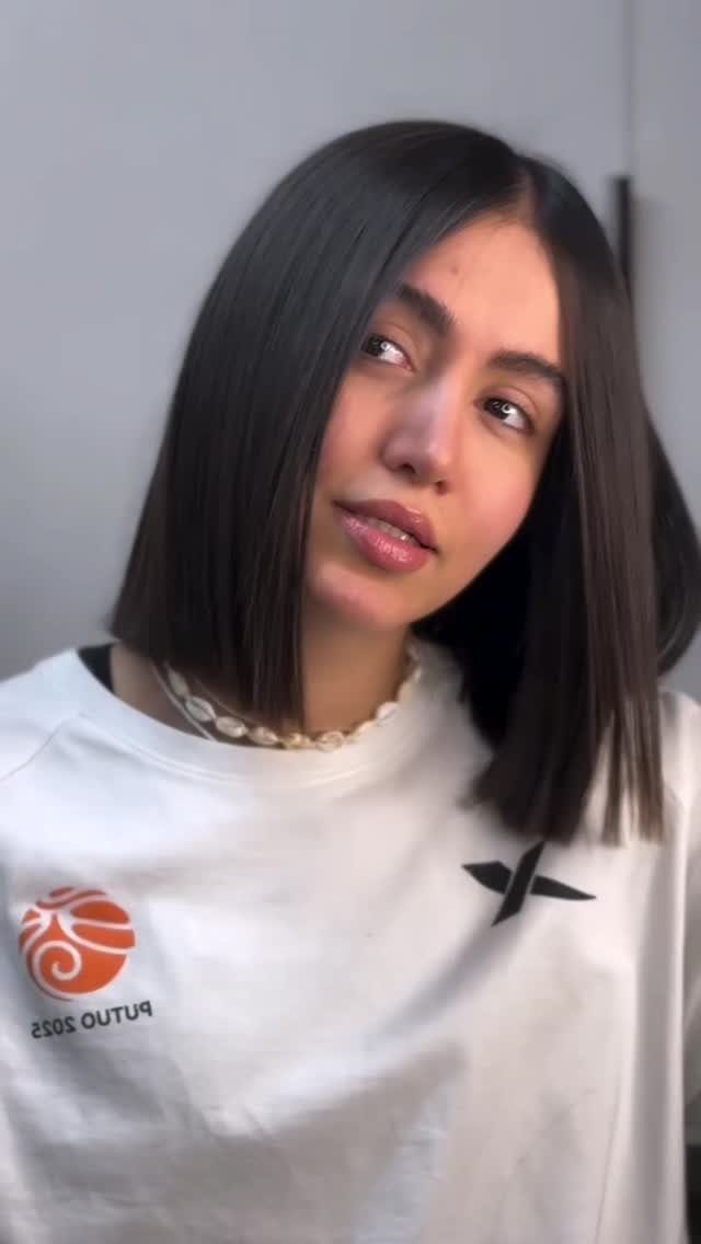 Woman with a straight, dark, center-parted bob and white T-shirt