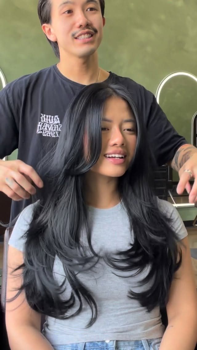 Long black face-framing layers sweep around a woman’s face and curl outward at the ends