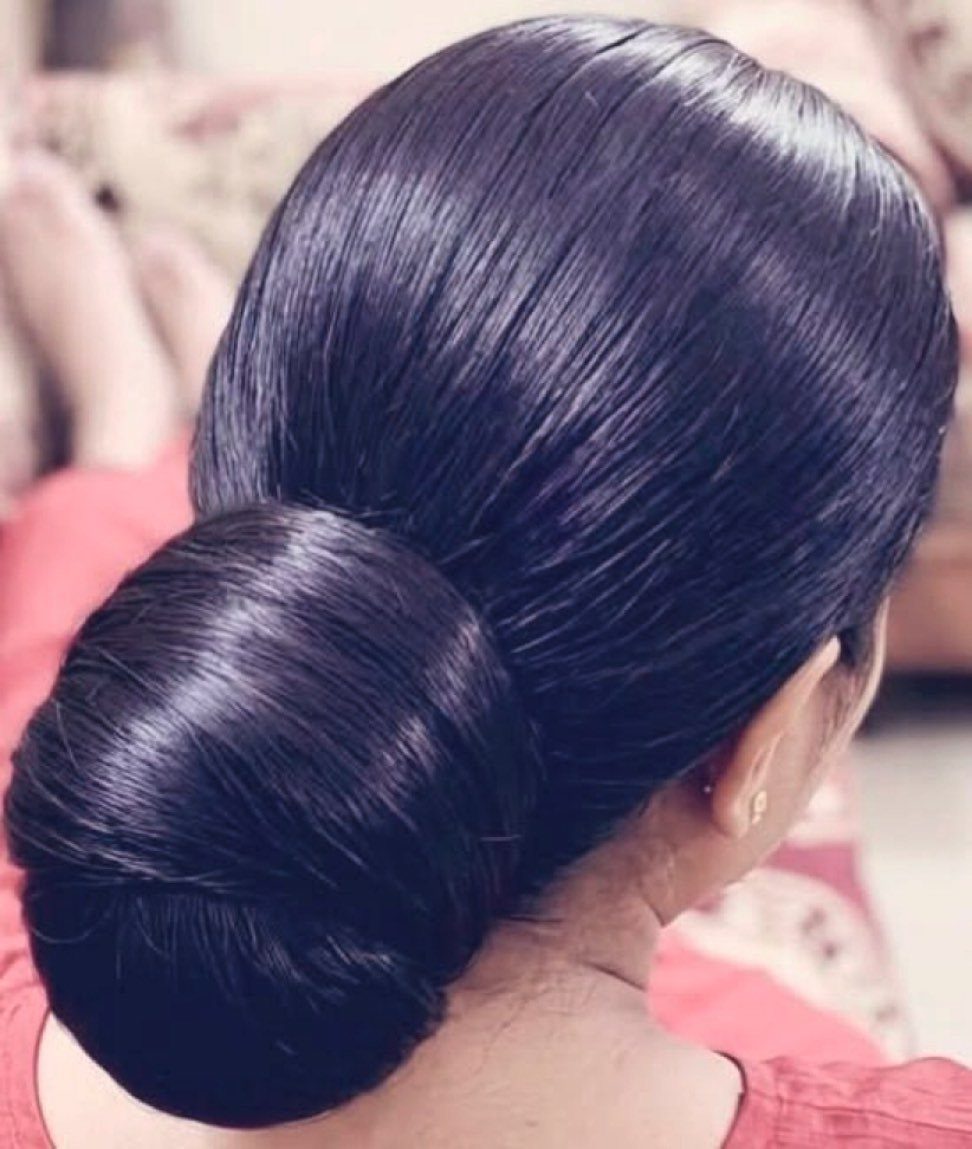Glossy dark hair smoothed into a large low bun at the nape