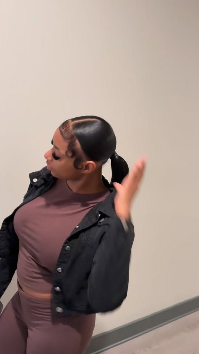 Person poses with sleek dark hair pulled into a low ponytail