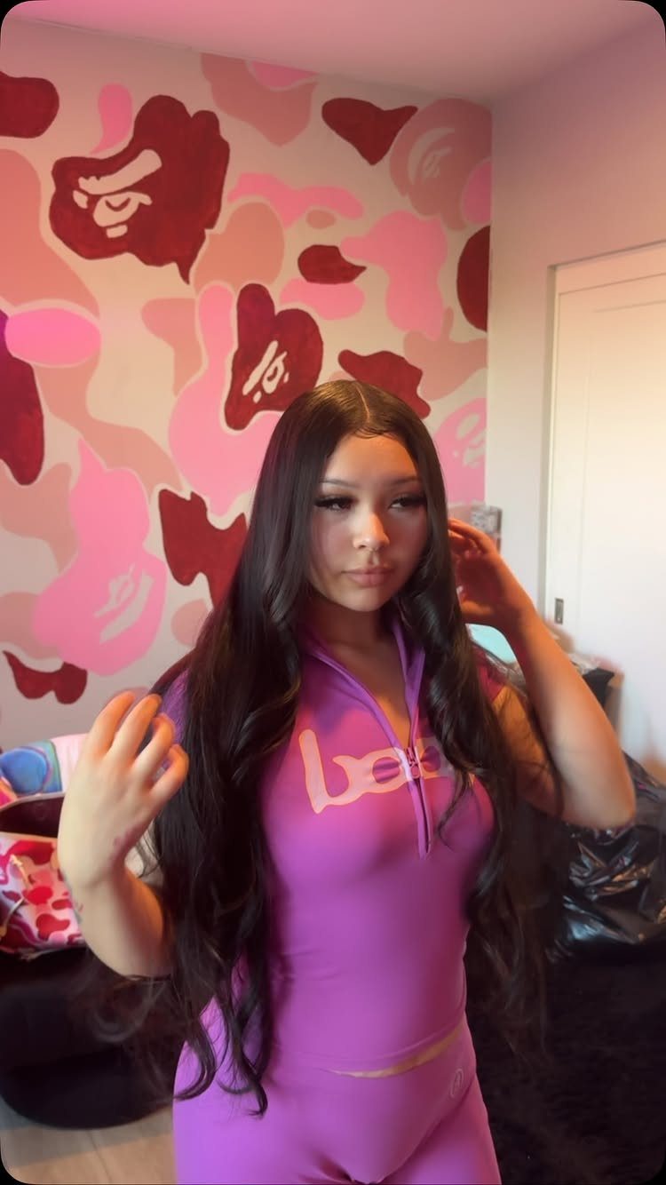 Woman showing long dark hair with a near-center part in a colorful room