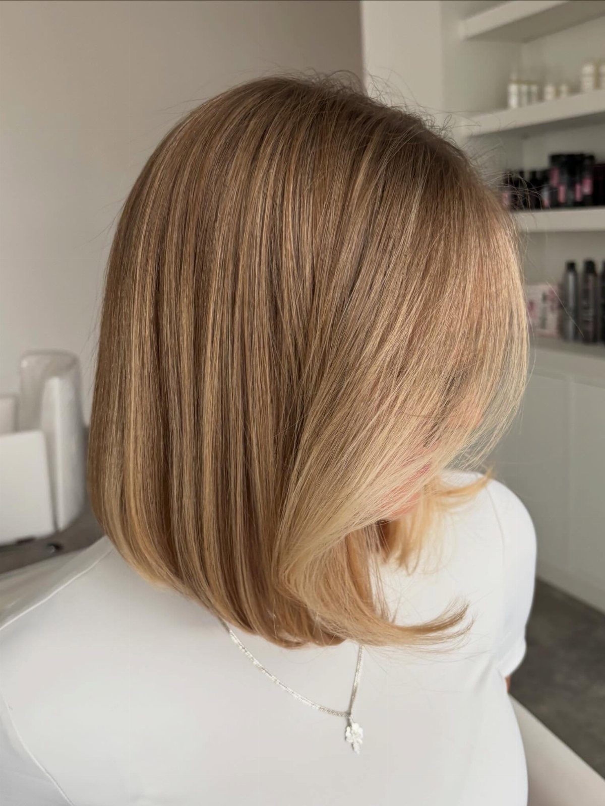 Straight bob with warm blonde highlights and softly curved ends in a salon