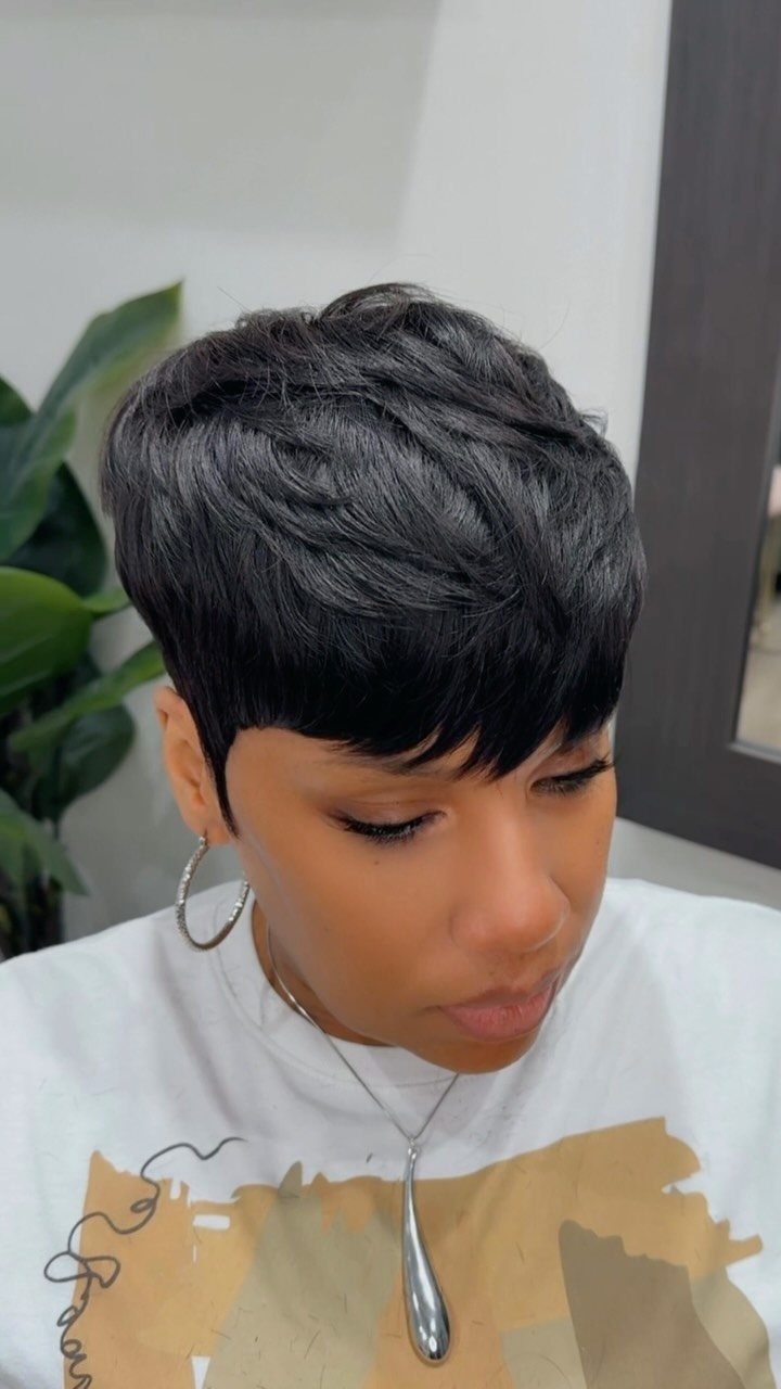 Short dark pixie haircut with choppy layers and a fringe across the forehead