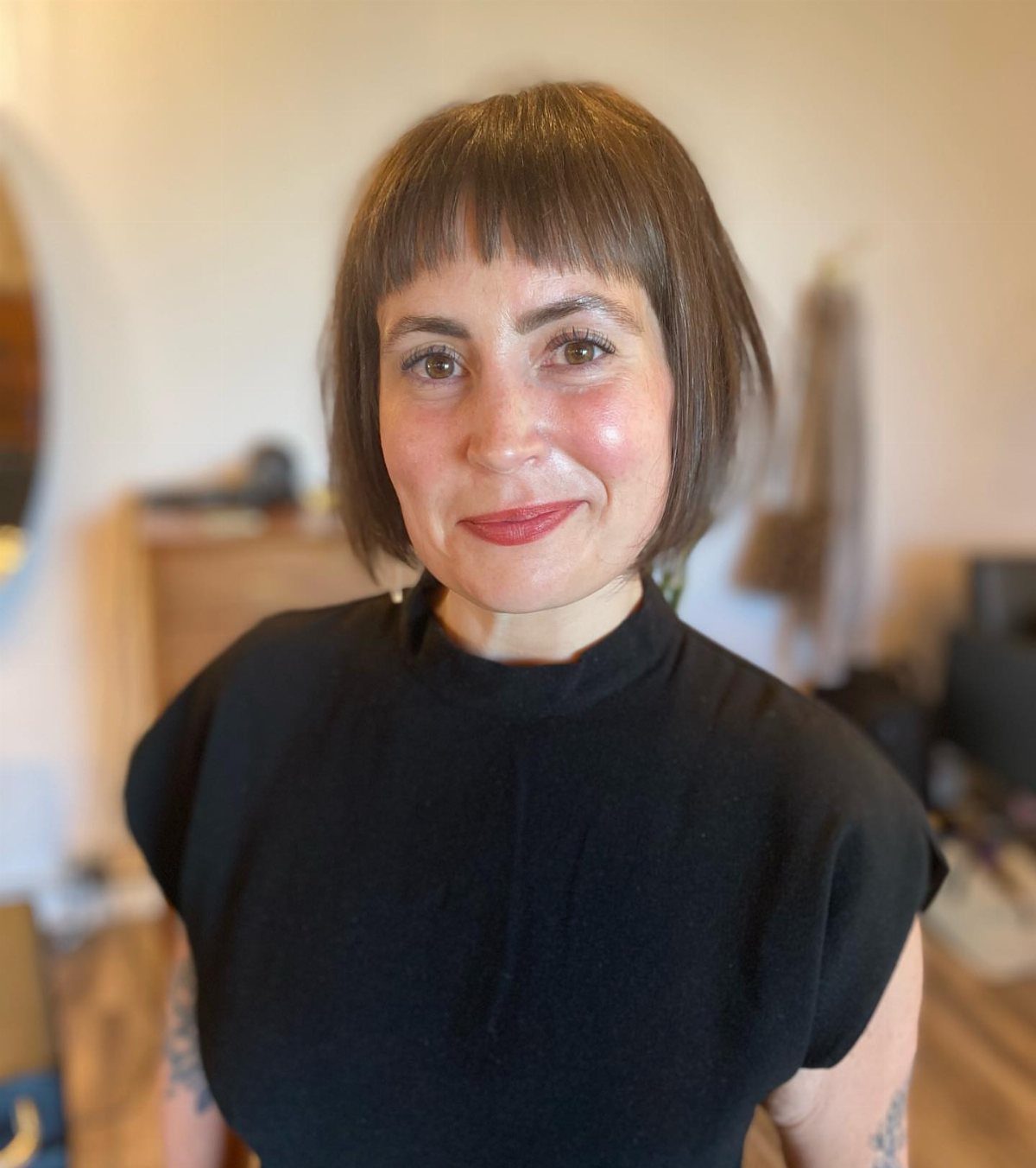 Woman with short brown textured crop haircut and blunt bangs