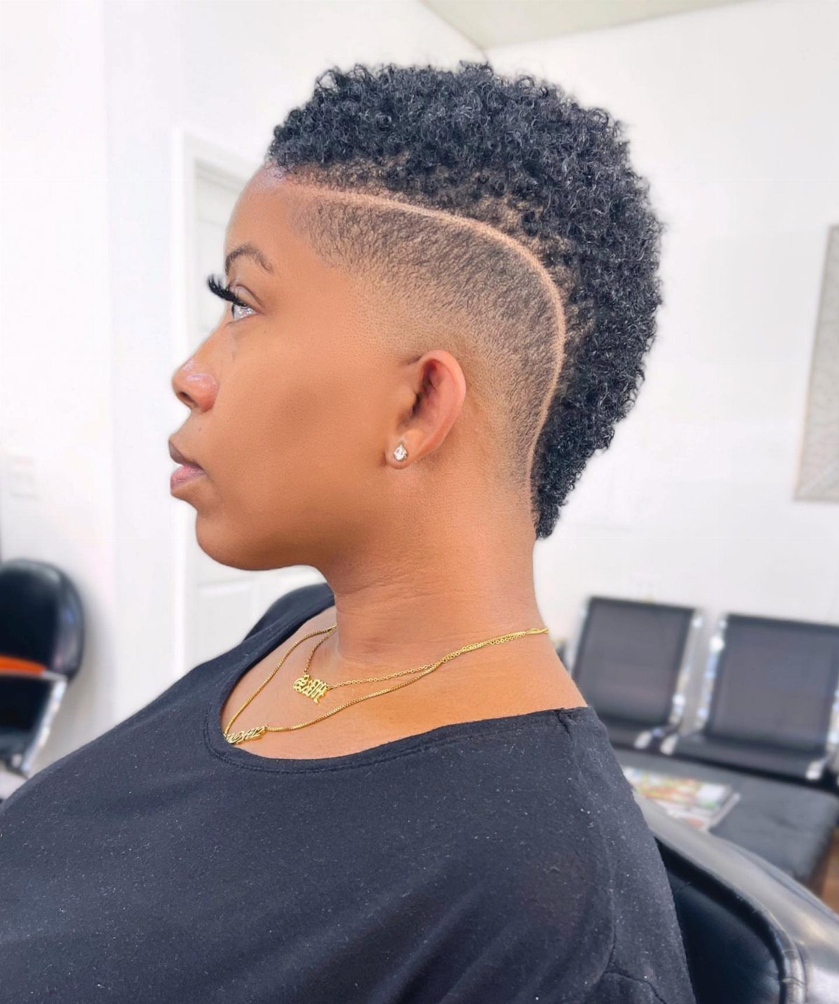 Profile of a person with curly cropped hair, shaved design line, and faded sides