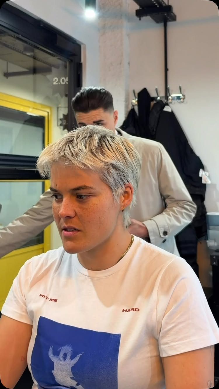 Short blond crop with forward fringe being styled in a barber shop