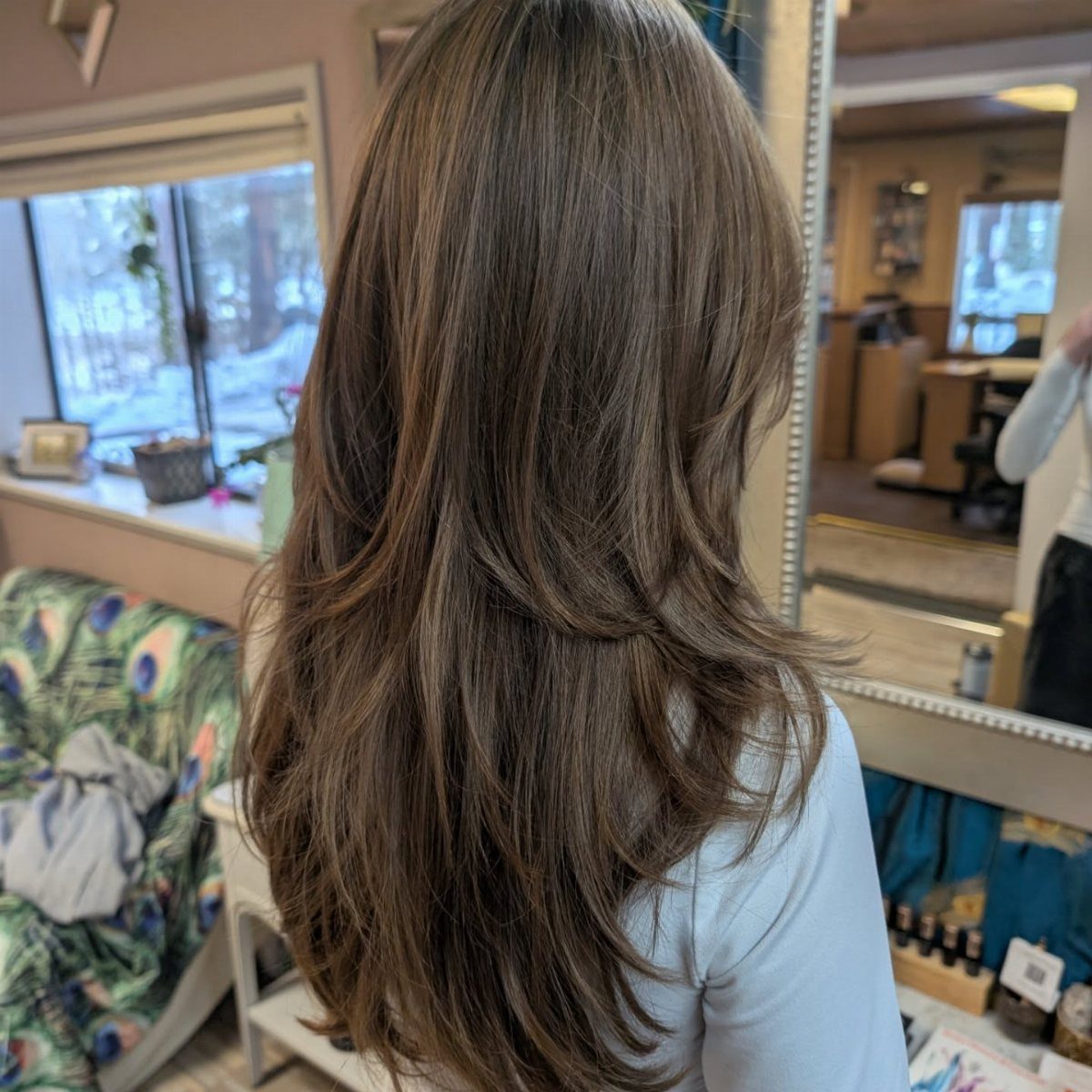 Long brown layered hair with blended waves and curled ends in a salon