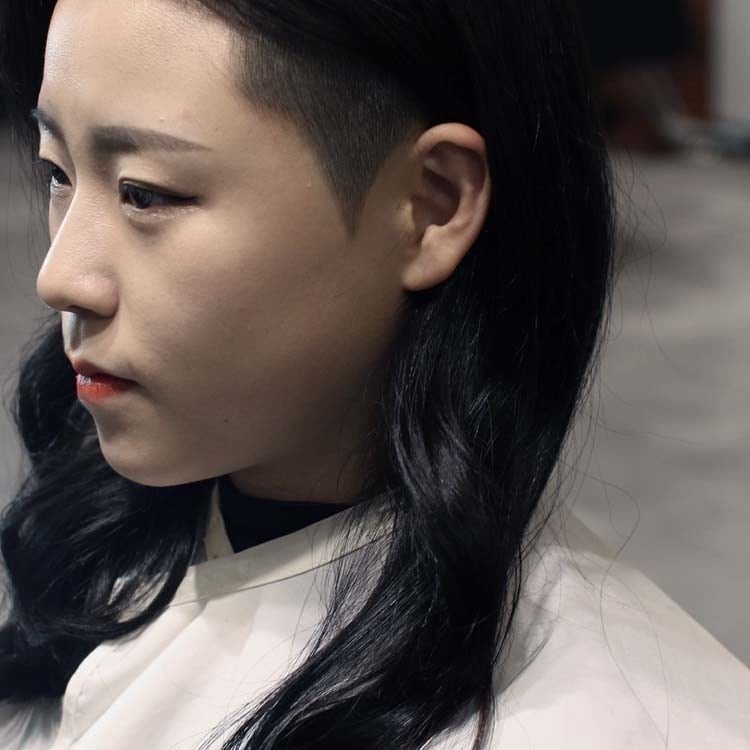 Person with long black hair and a shaved undercut above the ear