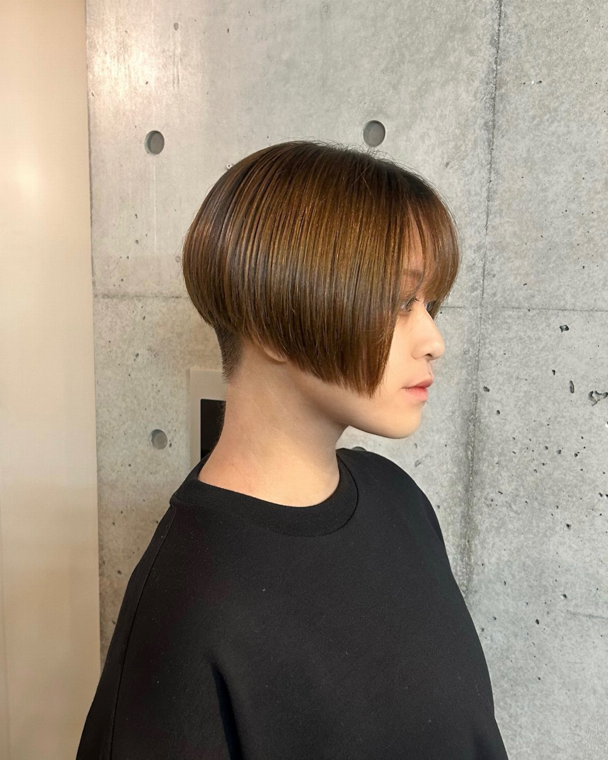 Profile showing a brown two-block haircut with long rounded top and cropped nape